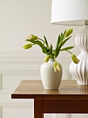 Blumenvase und Tischlampe auf Holztisch