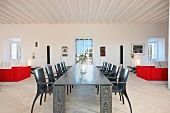 Esstisch und Stühle aus grau gebeiztem Holz und mit rote Sofagarnitur in offenem Wohnraum
