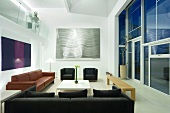 Wohnraum mit verschiedenen Polstermöbeln und moderner Kunst gegenüber raumhoher Fensterfront