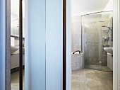 View through a door of a glass enclosed shower stall in the corner of a modern bathroom