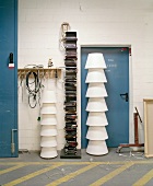Stacked white lampshades in front of metal door next to modern bookcase