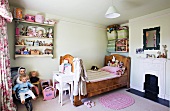 Solid wood bed, open fireplace and arranged dolls and soft toys in corner of child's bedroom with nostalgic ambiance