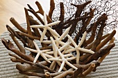 Dried starfish in original bowl of woven roots on wicker mat