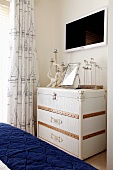 White steamer trunk as maritime chest of drawers in bedroom with blue, quilted bedspread in foreground