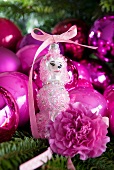 Pink Christmas tree baubles and dog figurine on fir branch