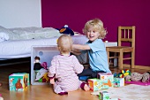 Siblings playing together in bedroom