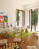 Modern child's bedroom with white shell chairs and table on green rug in front of open terrace door