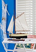 Segelboot, Fischnetz & Metallschilder als maritime Zimmerdeko
