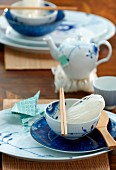 Asiatisches Gedeck - Stäbchen und Reisnudeln in Schale vor Teekännchen