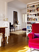 Teilweise sichtbarer roter Sessel und Bücherregal neben raumhohem Durchgang und Blick in Vorraum