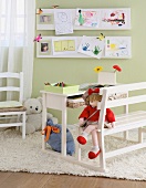 Kindermöbel - Möbelobjekt aus Tisch und Bank auf Teppich vor grüner Wand mit Kinderzeichnungen