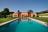 Ein langer Pool mit mediterranem Poolhaus in einer gepflegten Gartenanlage