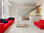 Rote Sitzmöbel auf hellem Steinboden in offenem Wohnraum mit Treppe