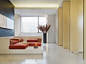 Sofa-Objekt mit Polstern auf Podest vor Wand aus drehbaren Raumteilern