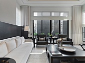 Langes Sofa und grosser Holztisch im schwarzweissen, modernen Wohnraum