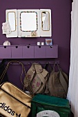 Purple, wall-mounted drawer unit and bags and backpacks hanging from coat rack on purple wall