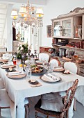 Gedeckter Tisch in Wohnraum mit antike Stühlen & Buffetschrank