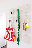 Ladies' accessories and keys hanging on white retro coat rack with shiny metal hooks
