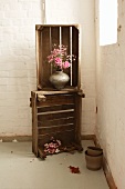 Two wooden boxes stacked on top of one another with a bouquet of roses in the corner of a room