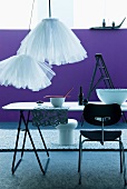 Simple dining table and contemporary tulle lampshades in front of purple wall and grey long-pile rug
