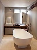 Free-standing designer bathtub in front of rustic wooden washstand