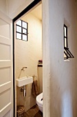 Blick in ein Gäste-WC mit alten Eisenfenstern und traditioneller Kalksteinwand