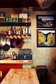 Vintage kitchen with simple, old wooden furniture and open grocery shelves next to modern landscape paintings on marbled wall