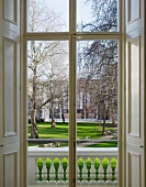 View through a French door with interior shutters of the manicured grounds of London's Goethe Institut