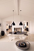 View over a counter with a bowl into a black and white dining area under retro hanging lamps