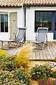 Blooming flowers on a terrace with loungers made of weathered wood at a country home
