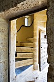 Blick durch Türöffnung auf gewendelte Steintreppe in rustikalem Haus