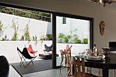 Dining area in front of partially open terrace window showing view of Butterfly chairs in various colours
