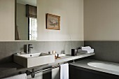 Minimalist washstand counter against half-height splashback on pale grey wall