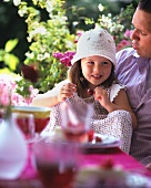 Little girl sitting on her father's lap eating cherries