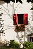 Ligurisches Landhaus mit roten Fensterläden und blühenden Hängegeranien