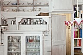 weiße Küchenwand im Shabby Stil mit Vitrine und umfangreicher Geschirrsammlung