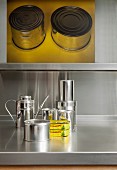 Metal still-life - storage jars on stainless steel worksurface and graphic artwork on wall