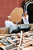 Couple filling skip with rubble