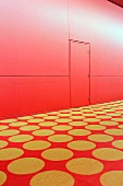 Roter Teppich mit gelben Punkten vor roter Wand