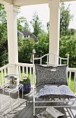 Side table & white metal chair with paisley cushions on veranda