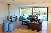 Modernes, helles Wohnzimmer mit großer Glasfront, Ledersofas und originellen Sesseln in Blütenform