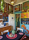 Künstlerisch inspirierte Küchengestaltung mit naiver südafrikanischer Malerei an den Wänden und Tischdecke mit Folkloremuster