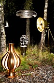 Various lit lamps arranged in front of birch trunks in dark woods at night