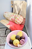 Fruit and rose in dish; garden chair with Oriental blanket and floral bolster in blurry background