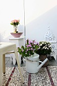 Bouquet of phlox in watering can on sequinned rug, white Marrakesh lamp and side table in background create Oriental atmosphere on roof terrace