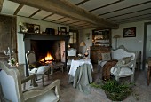 Cosy room with fireplace, low beamed ceiling and brick floor; vintage seating in front of open fire