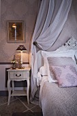 Grand bed with grey and white bed linen and scatter cushions colour-coordinated with wallpaper
