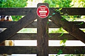 Australian Shepherd behind garden gate with warning sign in French