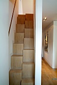 Space-saving staircase in narrow stairwell and view into modern hallway