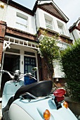 Vintage scooter parked in front of English-style terraced house